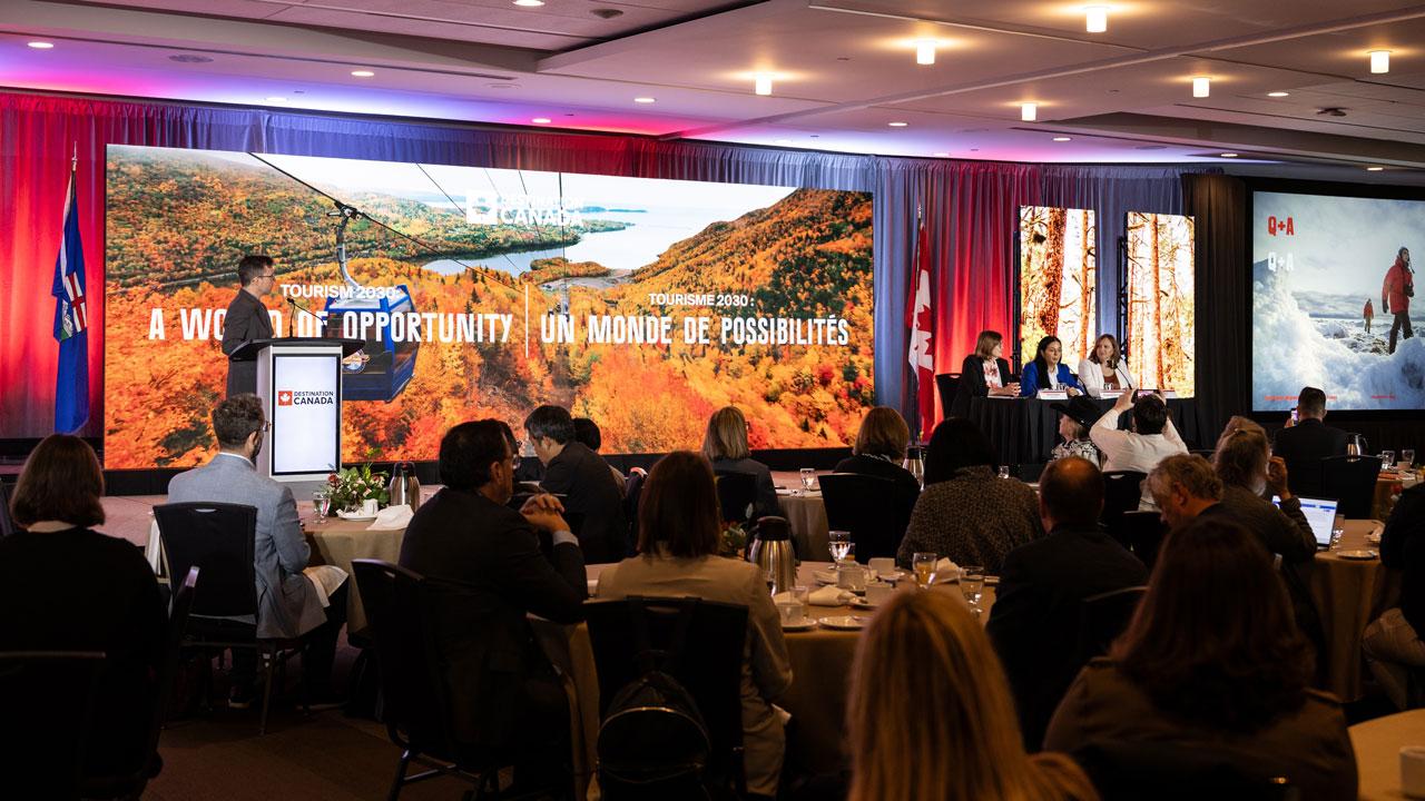A panel of presenters on stage with a Tourism 2030 banner behind them