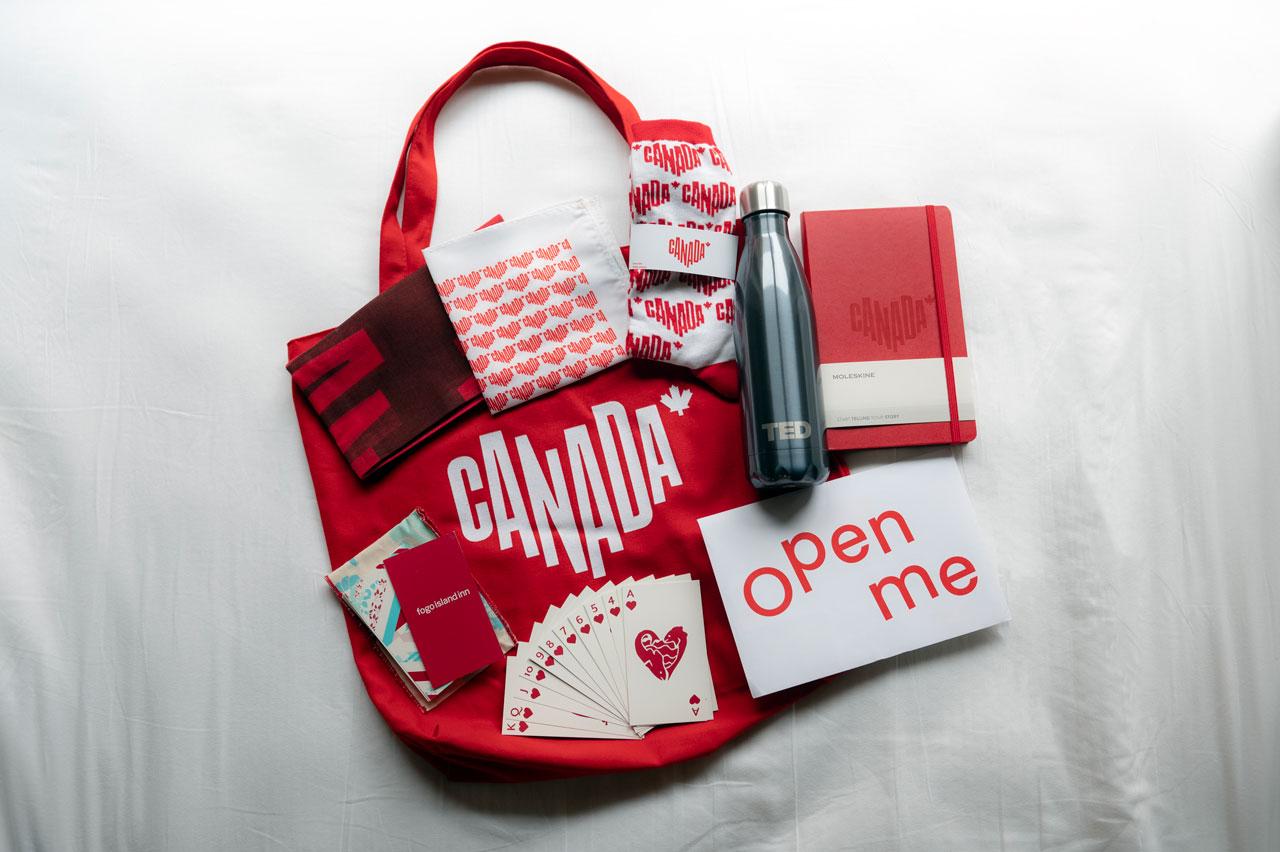 Différents articles promotionnels de Destination Canada comme un sac, une bouteille, un jeu de cartes, des chaussettes et un calepin.