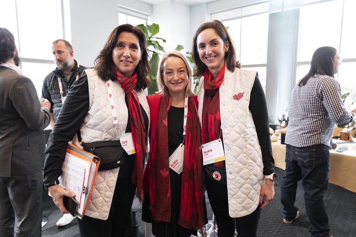 Three people smiling and wearing branded red scarfs and white vests featuring the Glowing Hearts logo